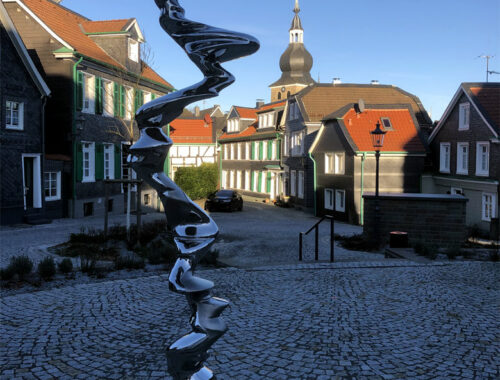 Fotografie Lennep Munsterplatz Richtung Stadtkirche. Die Fotografie zeigt die Skulptur "Der Pfad" im Vordergrund. Fotografiert am 11.01.2024 sonnig, klarer blauer Himmel